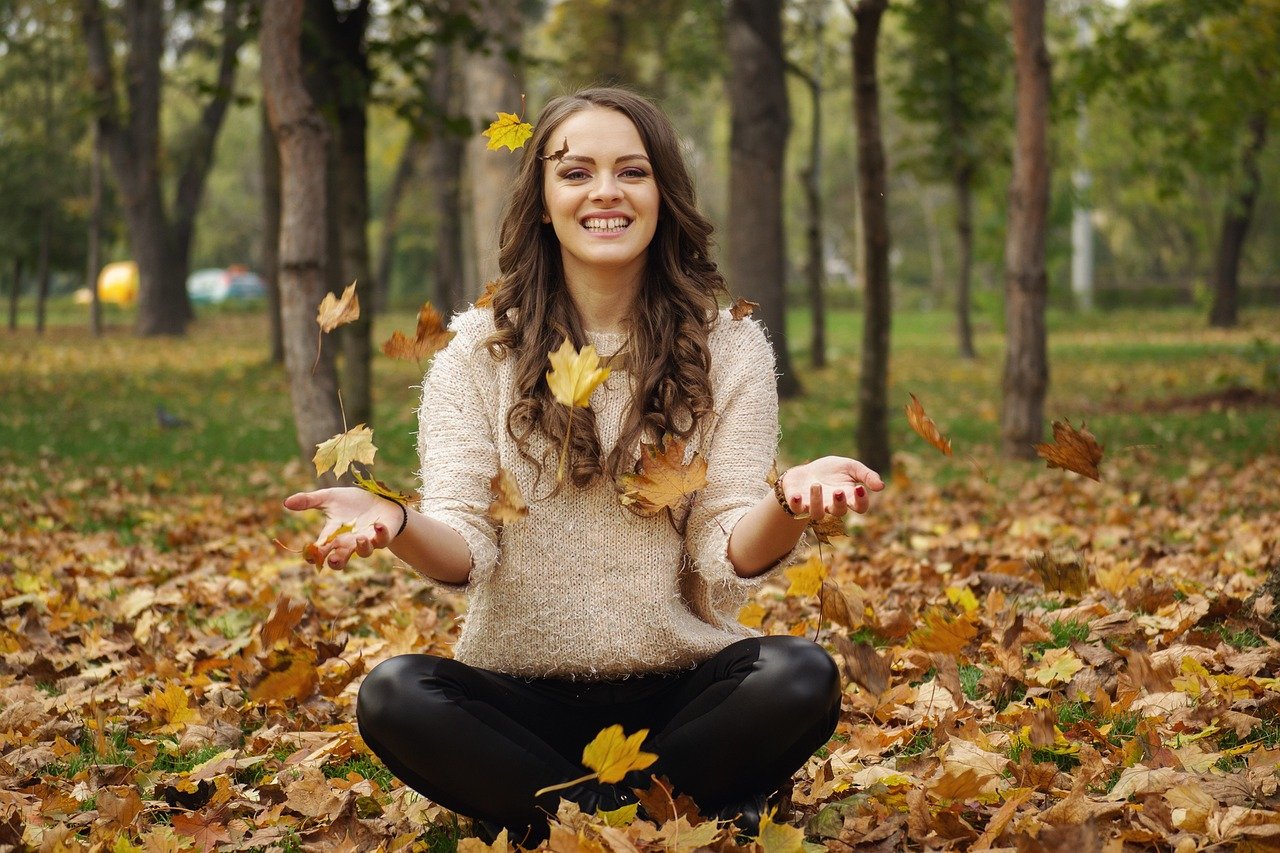 Mujer en calma al aire libre, entre hojas de otoño